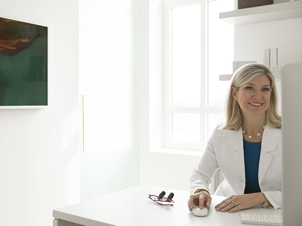 Dr Lindsey Marshall sitting at her desk smiling