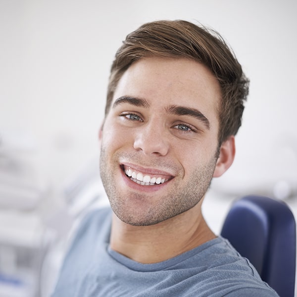 A man at the dentist smiling as he waits for his smile makeover treatment